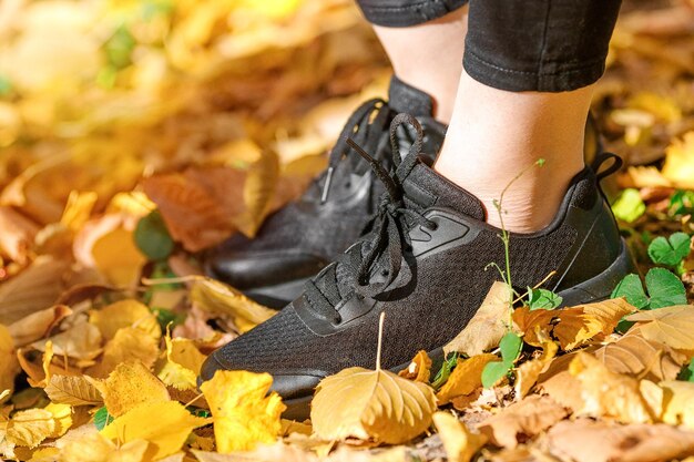 La partie inférieure de la femme debout au milieu des feuilles sèches