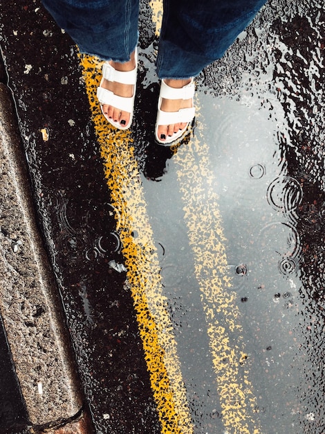 Photo la partie inférieure de la femme debout sur la route sous la pluie