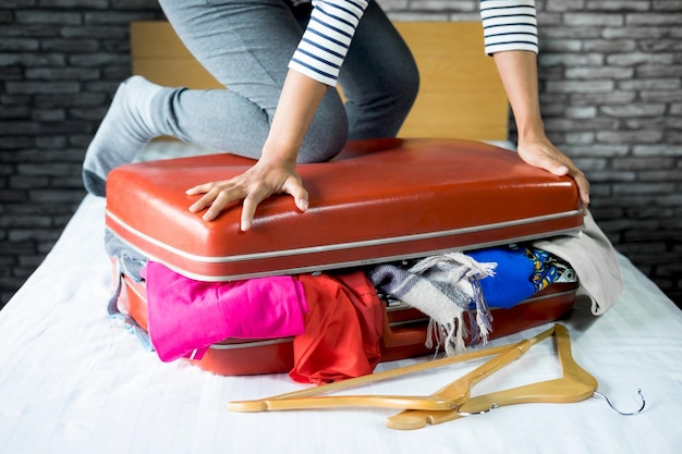 Photo la partie inférieure d'une femme emballant une valise sur le lit à la maison