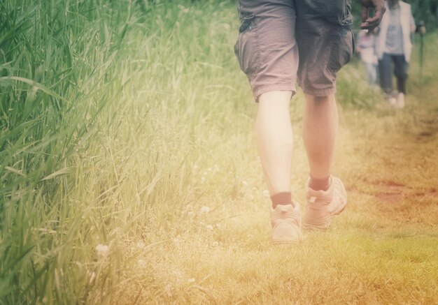 Photo la partie inférieure d'une femme marchant sur un champ herbeux