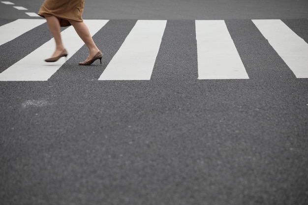 La partie inférieure d'une femme marchant sur un passage à zèbres