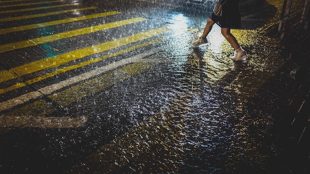 La partie inférieure d'une femme sur une route mouillée