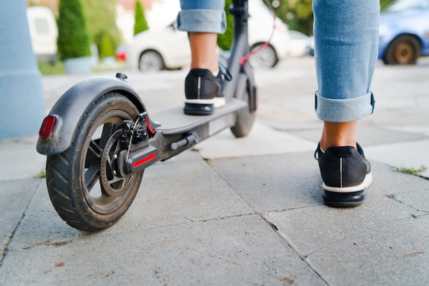 La partie inférieure d'une femme sur un scooter électrique sur un sentier piétonnier