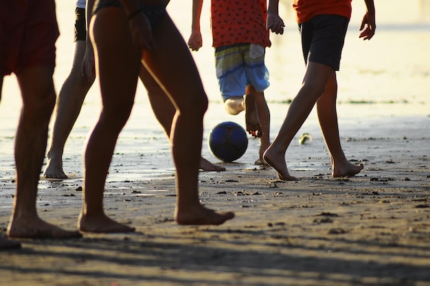Photo une partie inférieure des gens jouant au football sur la plage