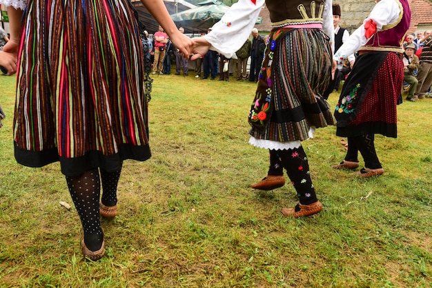 Photo la partie inférieure des gens portant des vêtements traditionnels tout en tenant les mains sur l'herbe