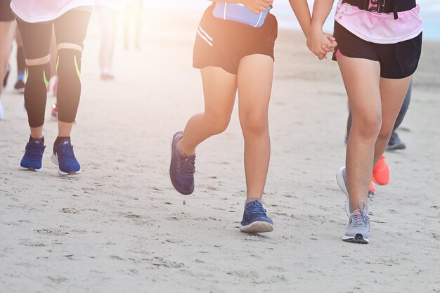 La partie inférieure des gens qui courent sur la plage