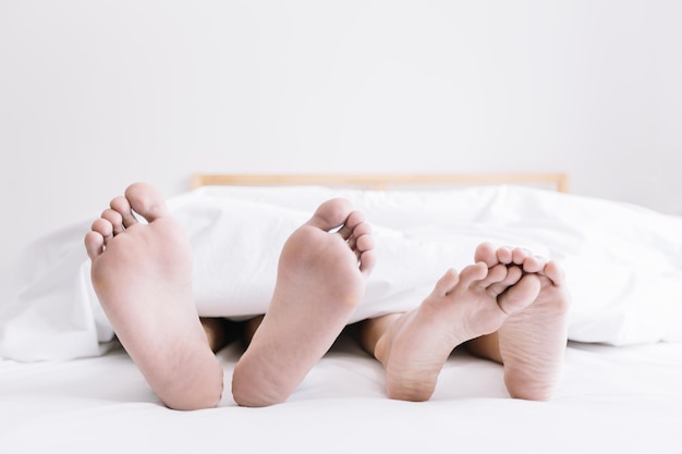 La partie inférieure des gens qui dorment sur le lit