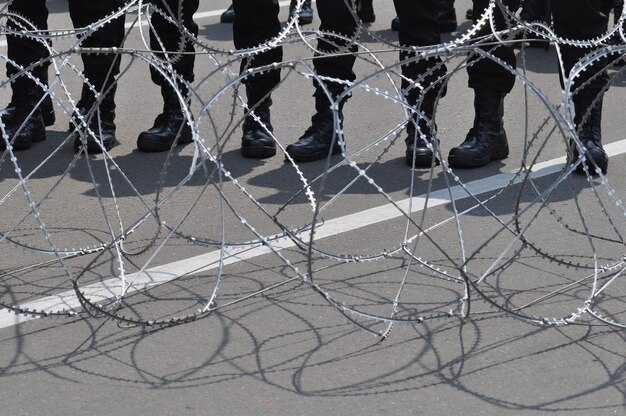 Une partie inférieure des gens en uniforme debout près de la clôture sur la route de la ville