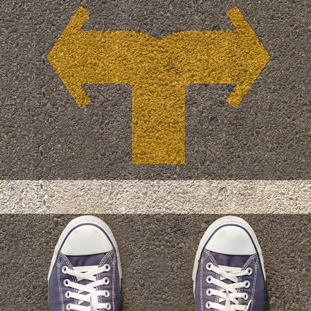 Photo la partie inférieure de l'homme debout par le symbole de la flèche sur la route