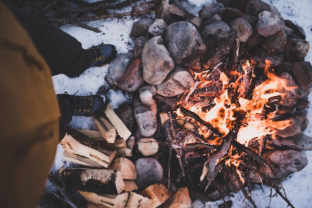 La partie inférieure de l'homme debout près du feu de joie pendant l'hiver
