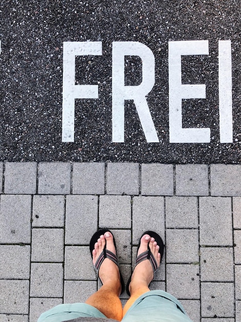 La partie inférieure de l'homme debout sur le trottoir par texte