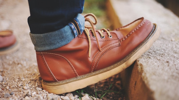 La partie inférieure de l'homme portant des chaussures alors qu'il se tient sur le trottoir