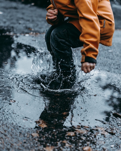 La partie inférieure de l'homme sautant sur une flaque d'eau