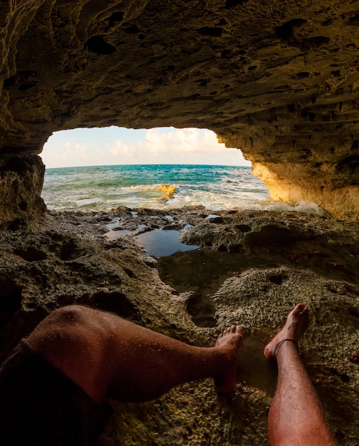 Photo la partie inférieure de l'homme se repose dans une grotte face à la mer.