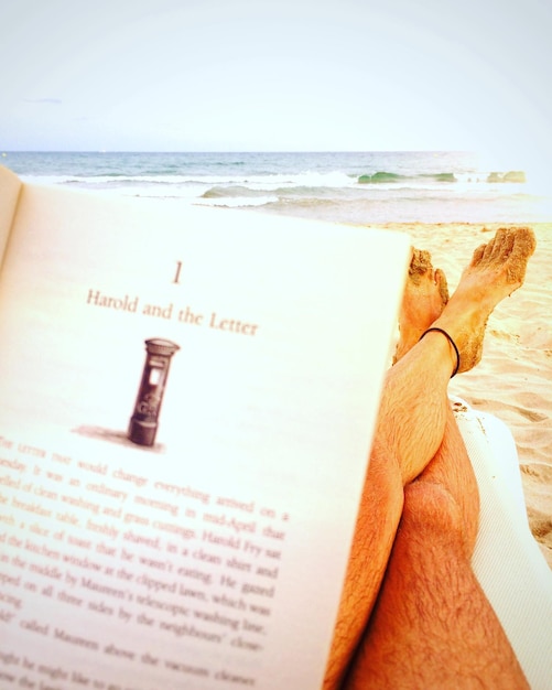 Photo la partie inférieure d'une personne avec un livre à la plage