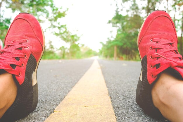 Photo la partie inférieure d'une personne portant des chaussures alors qu'elle est assise sur la route