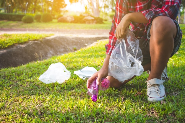 La partie inférieure d'une personne qui collecte des ordures sur un champ herbeux