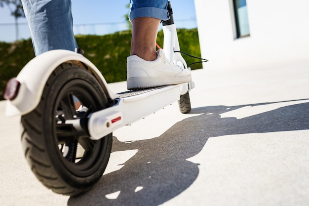 La partie inférieure d'une personne qui roule sur un scooter de poussée sur la route