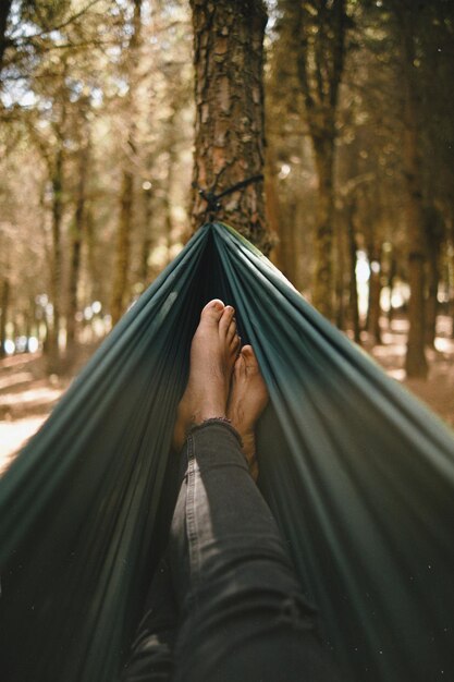 La partie inférieure d'une personne se détendant sur un hameau dans la forêt