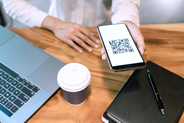 La partie inférieure de la personne tenant un téléphone intelligent sur la table