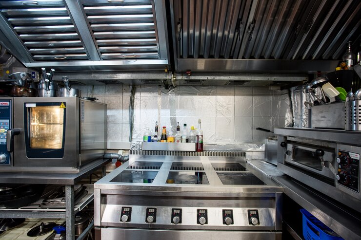 Photo partie de l'intérieur d'une grande cuisine de restaurant contemporain comprenant une cuisinière électrique et un four pour cuire et rôtir des aliments, des ustensiles de cuisine