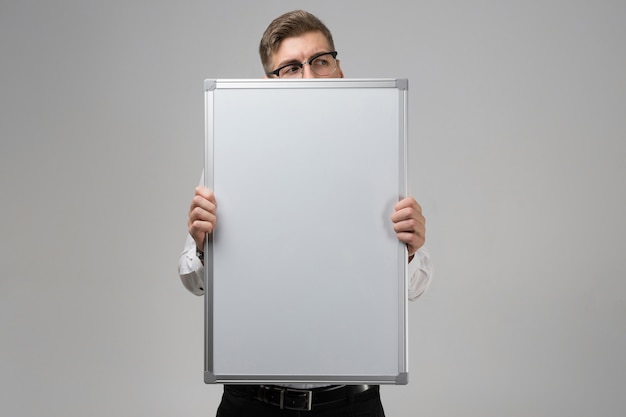 Partie de jeune homme portant des lunettes avec tableau magnétique propre dans ses mains isolées