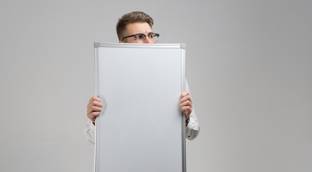 Partie de jeune homme portant des lunettes avec tableau magnétique propre dans ses mains