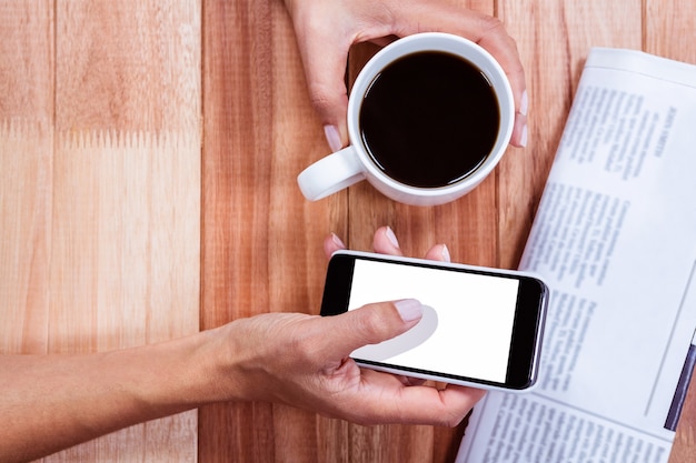 Partie de mains tenant le café et le smartphone