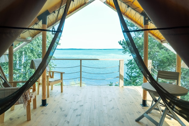 Partie de la maison de glamping avec table et chaises et océan bleu