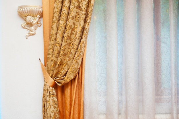Partie d'un rideau magnifiquement drapé et d'un mur avec des motifs