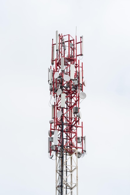 Partie supérieure de la tour radio avec antennes installées et autres équipements contre un ciel nuageux blanc