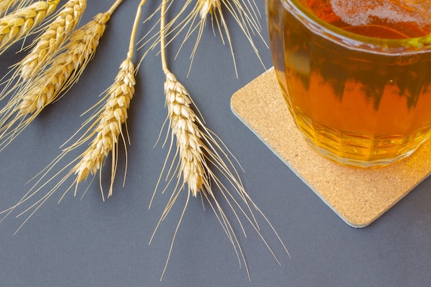 Partie d'une tasse en verre avec de la bière. Épis de blé