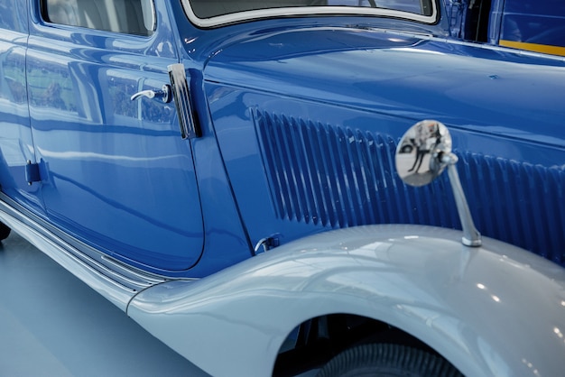 Une partie de la voiture vintage polie parfaite bleue debout à l'intérieur au carreau blanc.