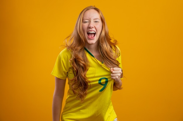 Partisan du Brésil. Fan de femme rousse brésilienne célébrant le football, match de football aux couleurs du Brésil.