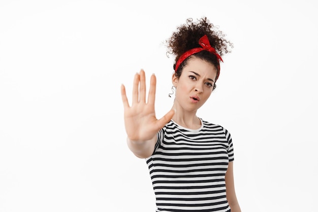 Pas assez de moyens Une femme sérieuse et déterminée a tiré sur le geste d'arrêt du bloc tendant la main et fronçant les sourcils interdire quelque chose de mauvais interdire refuser l'action fond blanc