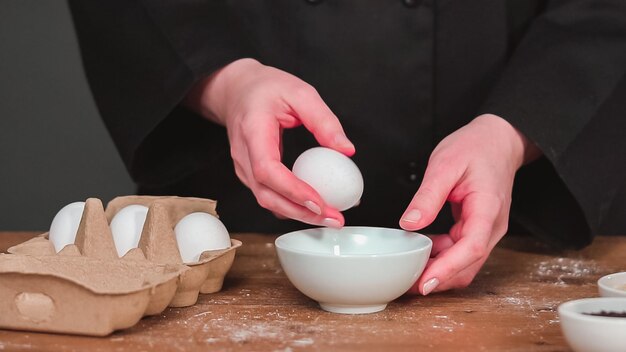 Pas à pas. Casser des œufs blancs biologiques dans un bol en verre.