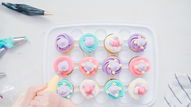 Pas à pas. Le chef pâtissier passe un glaçage à la crème au beurre sur des cupcakes de licorne pour la fête d'anniversaire d'une petite fille.