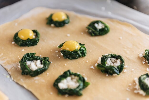 Pas à pas le chef prépare des raviolis avec de la ricotta, des jaunes d'œufs de caille et des épinards aux épices. Le chef prépare la garniture sur la pâte