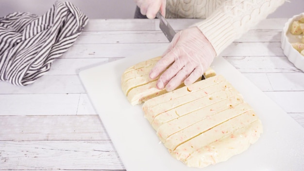 Pas à pas. Couper le fudge de canne en bonbon fait maison sur une planche à découper blanche.