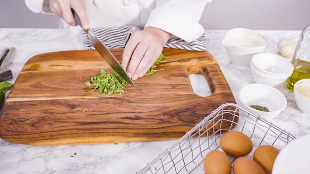 Pas à pas. Couper les ingrédients pour faire des gâteaux de courgettes avec de la crème sure aux herbes.