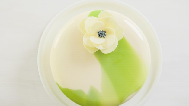 Pas à pas. Cuisson du gâteau mousse gourmand avec glaçage miroir blanc et vert décoré de fleur de chocolat blanc.