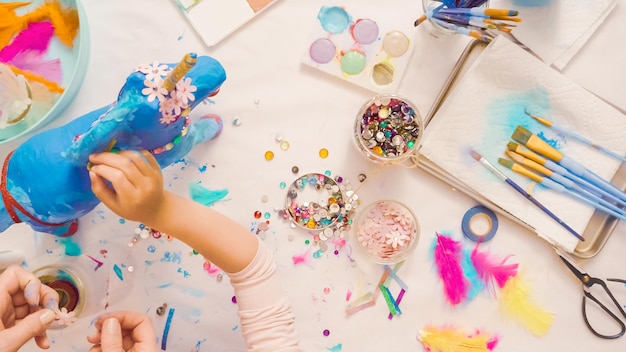 Pas à pas. décoration de licorne en papier mâché peint avec des fleurs et des bijoux en papier.