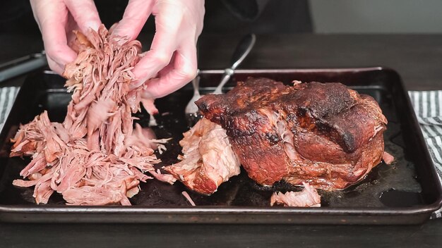 Pas à pas. Effilocher l'épaule de rôti de porc avec deux fourchettes.