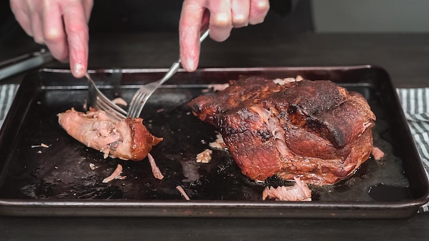 Pas à pas. Effilocher l'épaule de rôti de porc avec deux fourchettes.