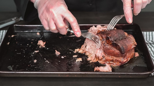 Pas à pas. Effilocher l'épaule de rôti de porc avec deux fourchettes.