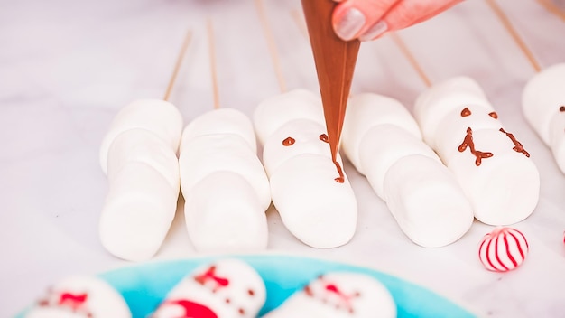 Pas à pas. Faire un bonhomme de neige à la guimauve et des rennes sur des bâtons de chocolat chaud pour offrir de la nourriture.