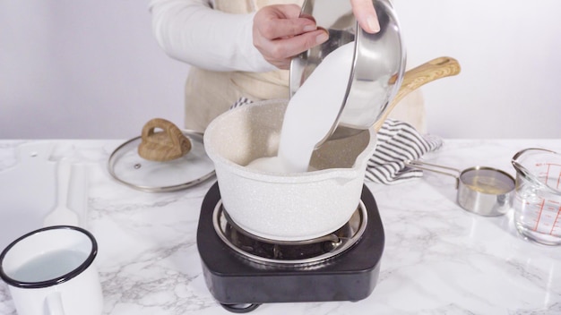 Pas à pas. Faire caraméliser le sucre dans une petite marmite au-dessus de la petite cuisinière électrique.