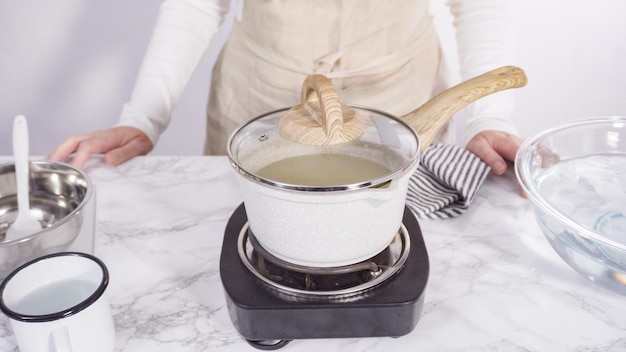 Pas à pas. Faire caraméliser le sucre dans une petite marmite au-dessus de la petite cuisinière électrique.