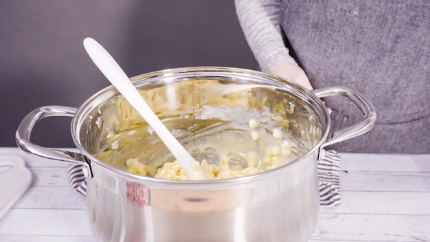 Pas à pas. Faire fondre des pépites de chocolat blanc dans la marmite pour faire du fudge au chocolat blanc à la canne de bonbon.