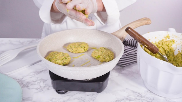 Pas à pas. Frire les galettes de courgettes dans l'huile d'olive sur une petite poêle.